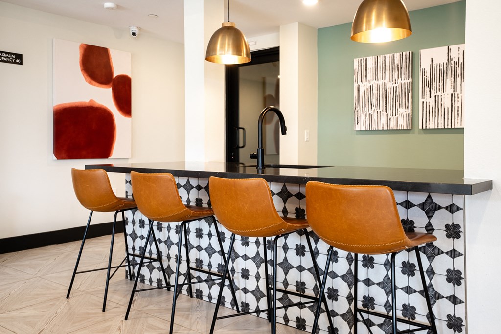 a kitchen with a large island with orange chairs and a painting on the wall