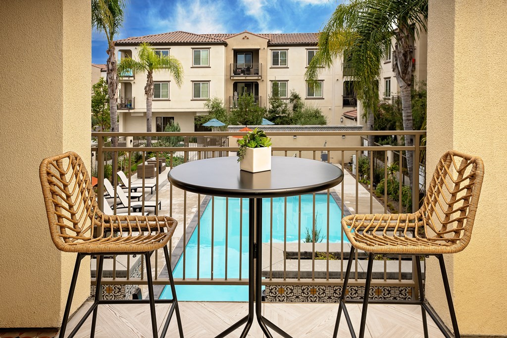 a patio with a table and chairs and a pool in the background