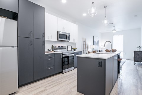 A modern kitchen with dark grey cabinets and a white countertop.