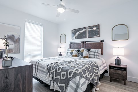 A bedroom with a bed, nightstands, and a ceiling fan.