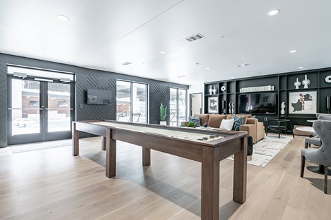 A modern living room with a long wooden table and a variety of seating options.