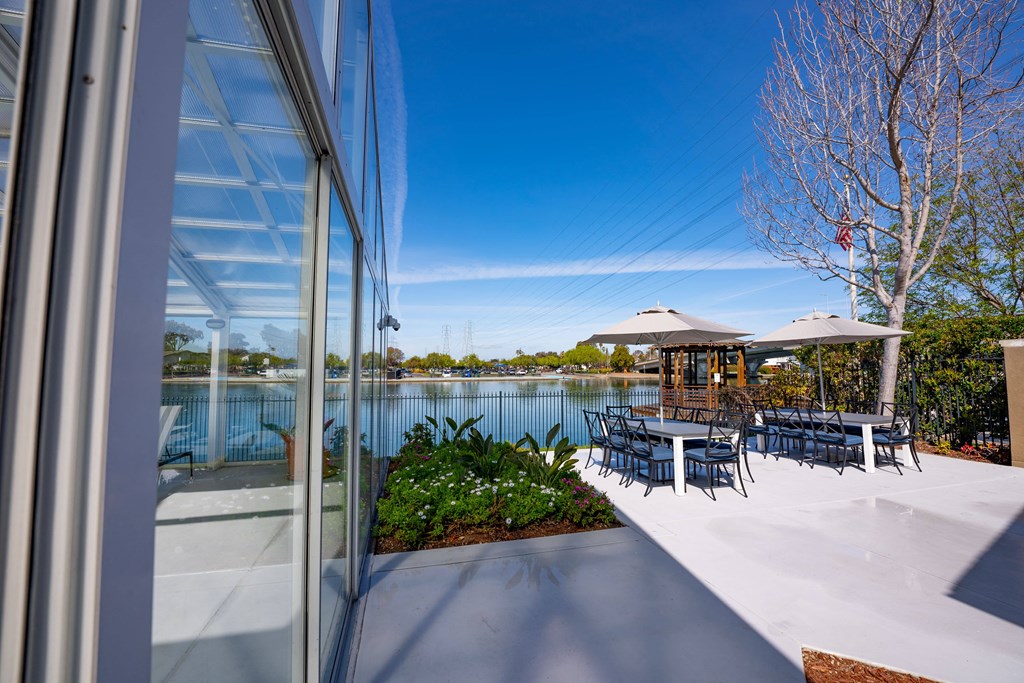 a patio with tables and chairs next to a body of water