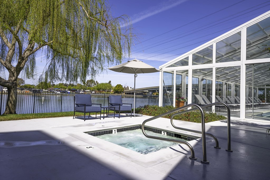 a jacuzzi and chairs in a patio next to a building