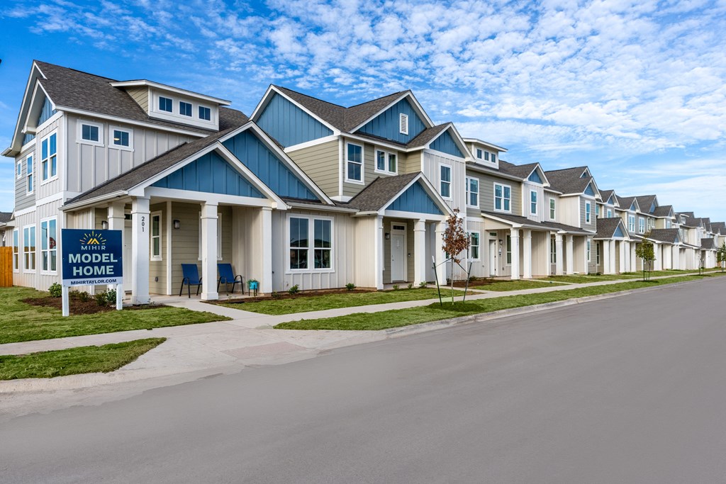 townhome exterior with green grass lawn at Mihir Taylor, Taylor, 76574