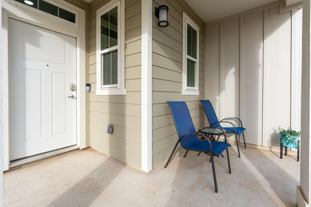 a porch with two blue chairs and a white door at Mihir Taylor, Texas 76574