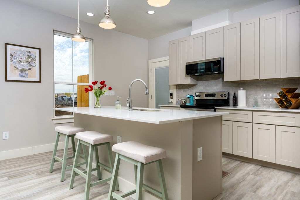 kitchen model with white cabinets and a large island with three stools at Mihir Taylor, Taylor, TX 76574