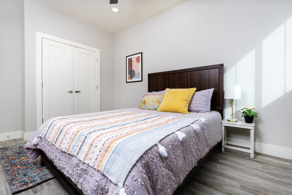 model bedroom with white walls and a bed with colorful pillows at Mihir Taylor, Taylor, TX