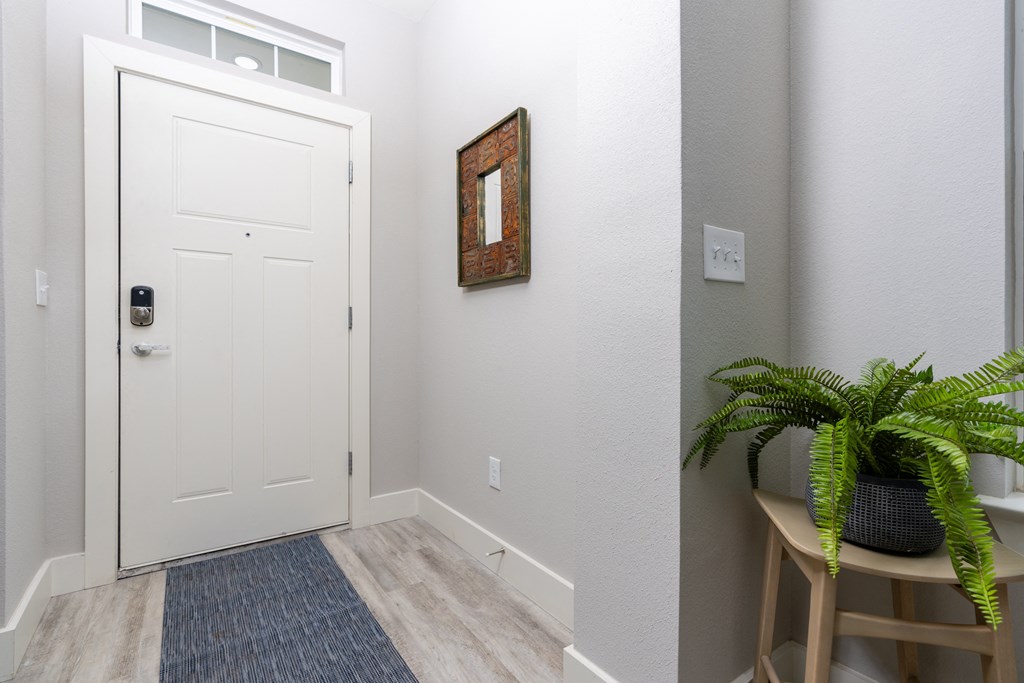 model entryway with a white door and a plant on a stool at Mihir Taylor, Taylor, Texas
