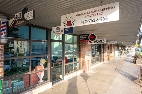 Strip mall storefronts with business signage at Mihir Taylor Apartments, Taylor