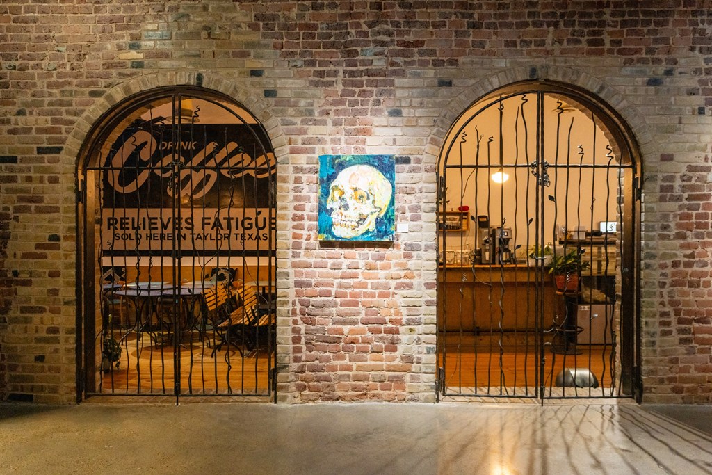 two arched doors with a bar and a sign on a brick wall at Mihir Taylor, Taylor, TX 76574