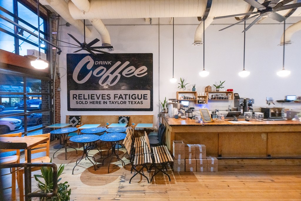 a coffee shop with blue tables and a sign that reads coffee reduces fatigue at Mihir Taylor, Texas 76574