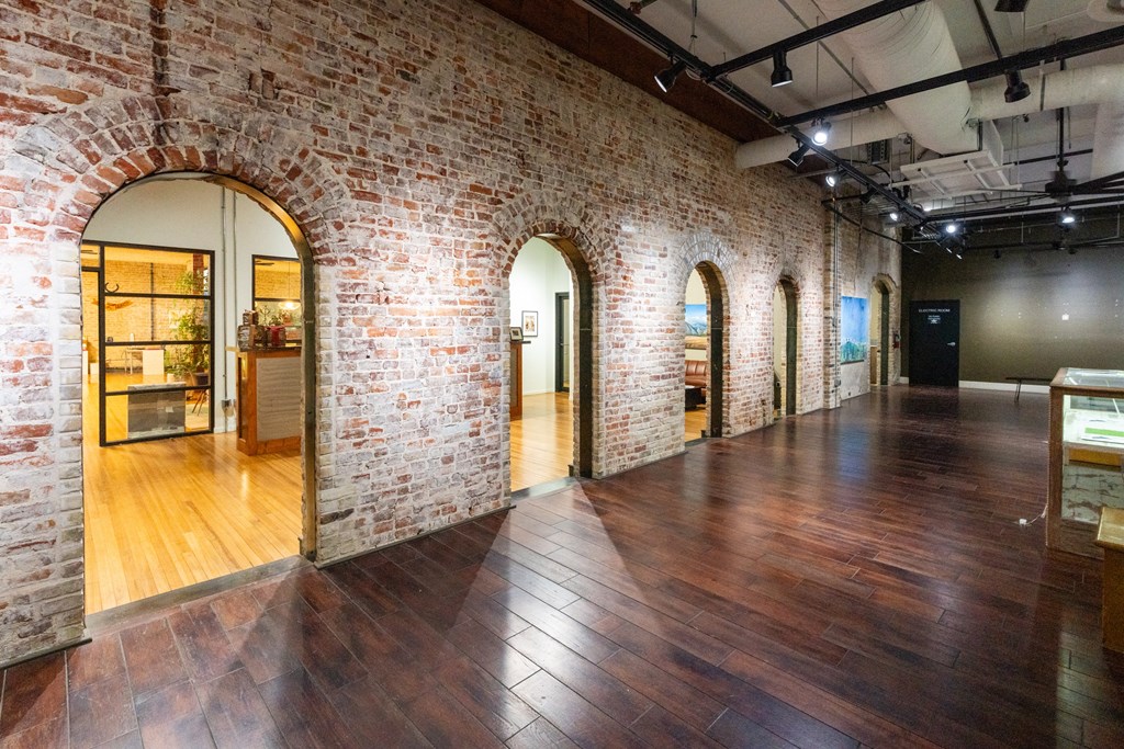 a large room with wood floors and brick walls and arched doorways at Mihir Taylor, Texas