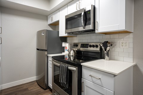 A modern kitchen with a black stove top oven and white cabinets.