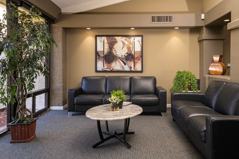 A living room with a large painting on the wall and a potted plant on the table.