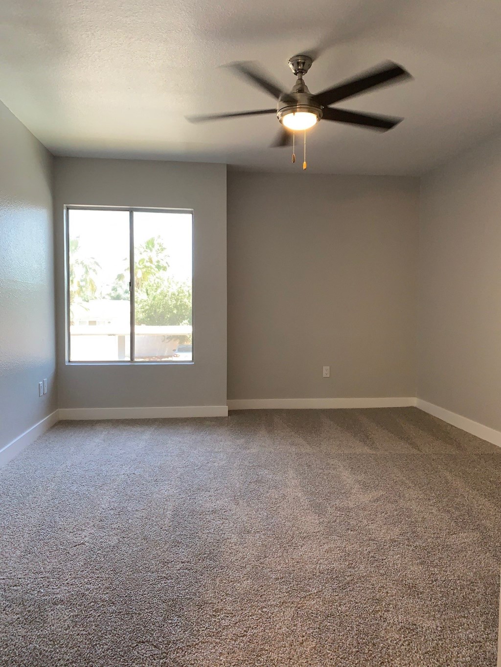 an empty living room with a ceiling fan and a window at Monaco at McCormick Ranch, Scottsdale, Arizona