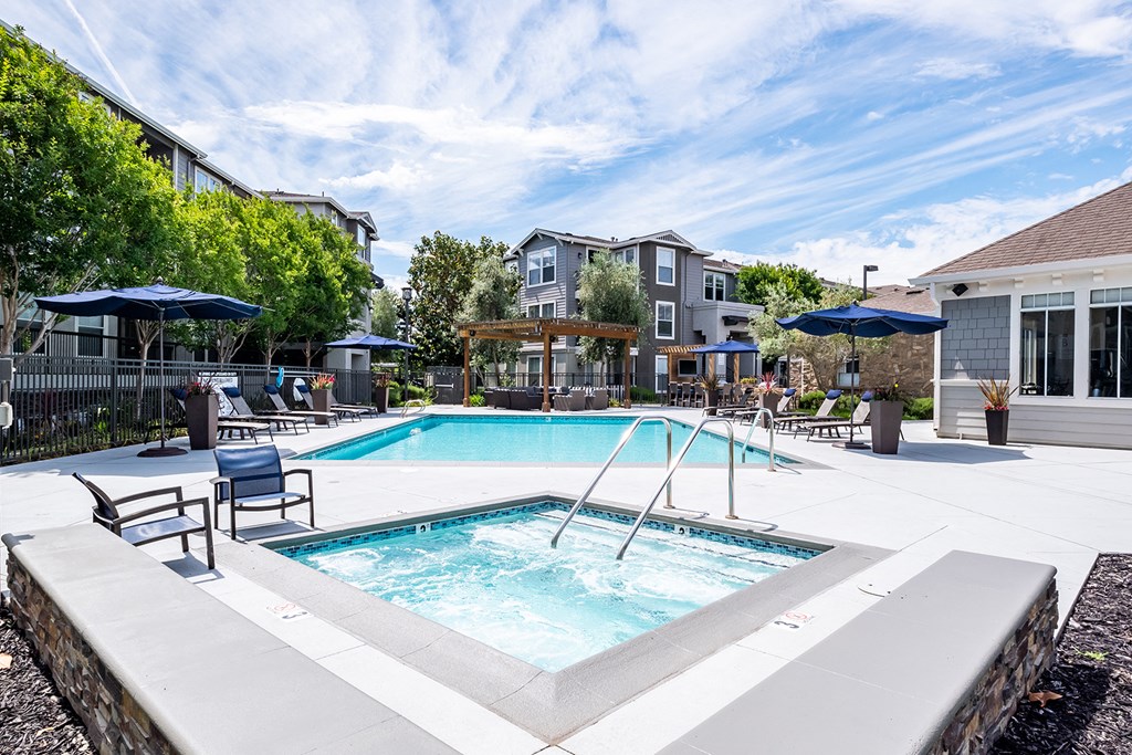 Outdoor pool and jacuzzi area with lounge chairs