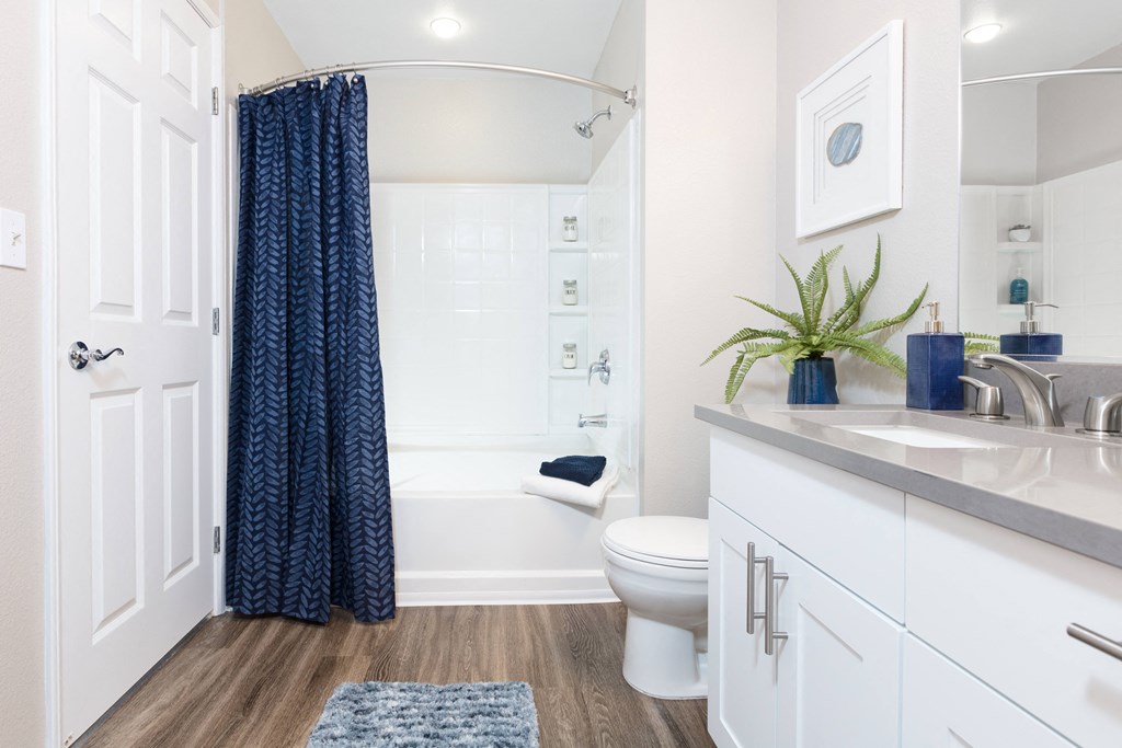 a bathroom with white cabinets and a blue shower curtain