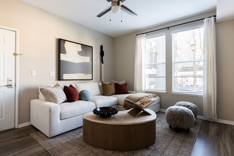 A living room with a white couch, a coffee table, and a ceiling fan.