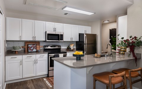 A kitchen with white cabinets and a grey countertop.