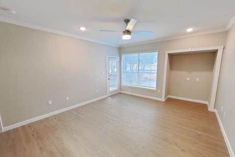 A spacious room with wooden flooring and a ceiling fan.