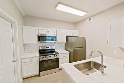 A kitchen with white cabinets and a stainless steel refrigerator.