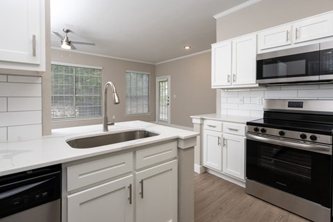 A kitchen with white cabinets and a black stove top oven.