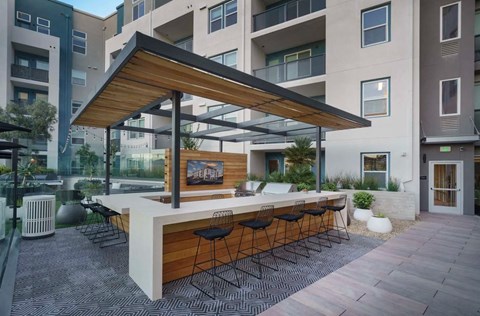 a patio with a bar and a large building in the background at NoMa Apartments, California