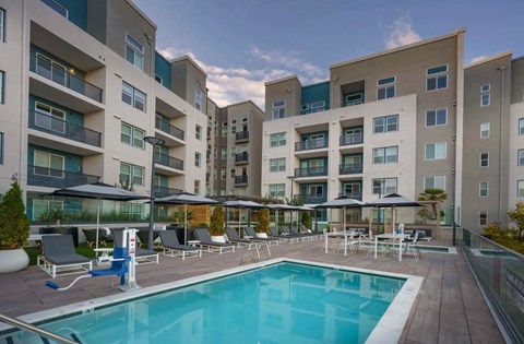Resort-Style Pool and Spa with Lounge Chairs and View of Building Exterior at NoMa Apartments, Walnut Creek, CA, 94596