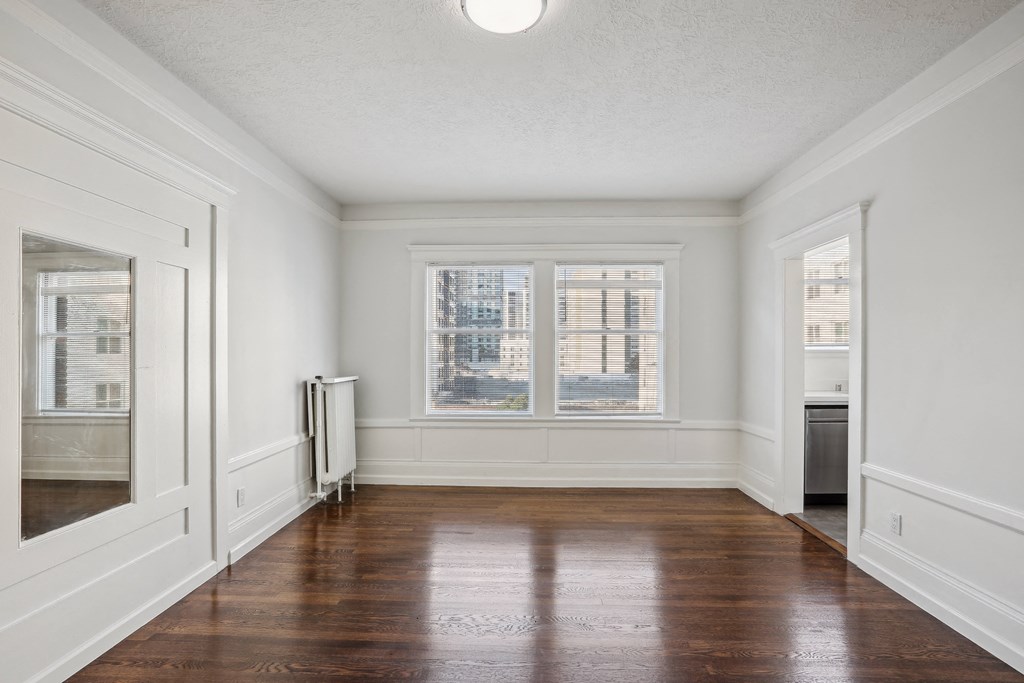 a bedroom with hardwood floors and white walls
