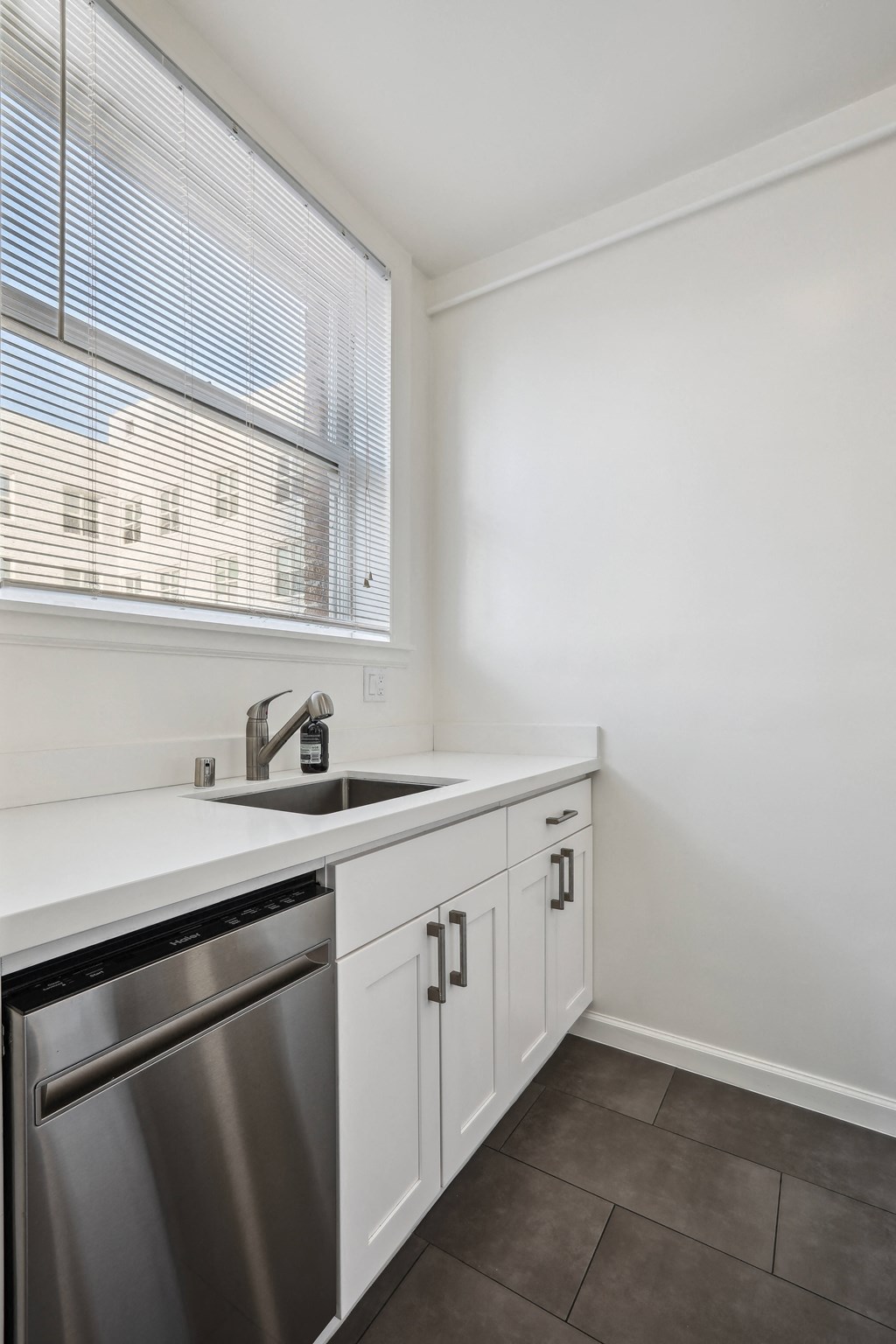 a kitchen with white cabinets and a stainless steel dishwasher
