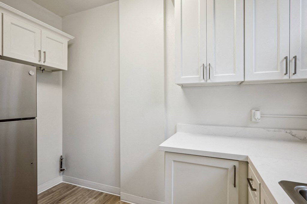 a kitchen with white cabinets and a stainless steel refrigerator