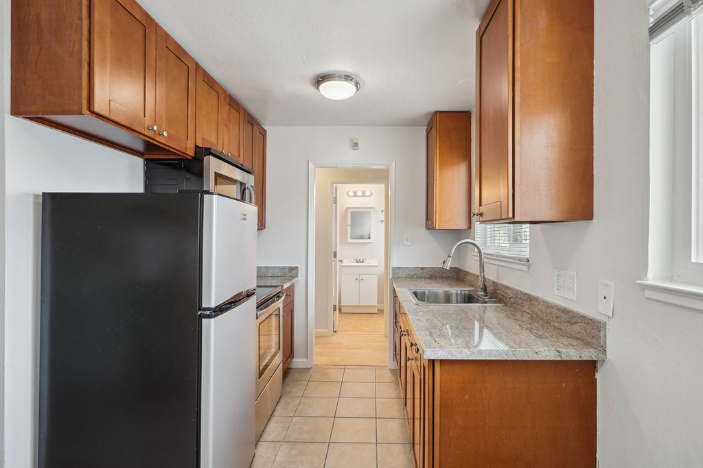 a kitchen with brown cabinets and a black refrigerator