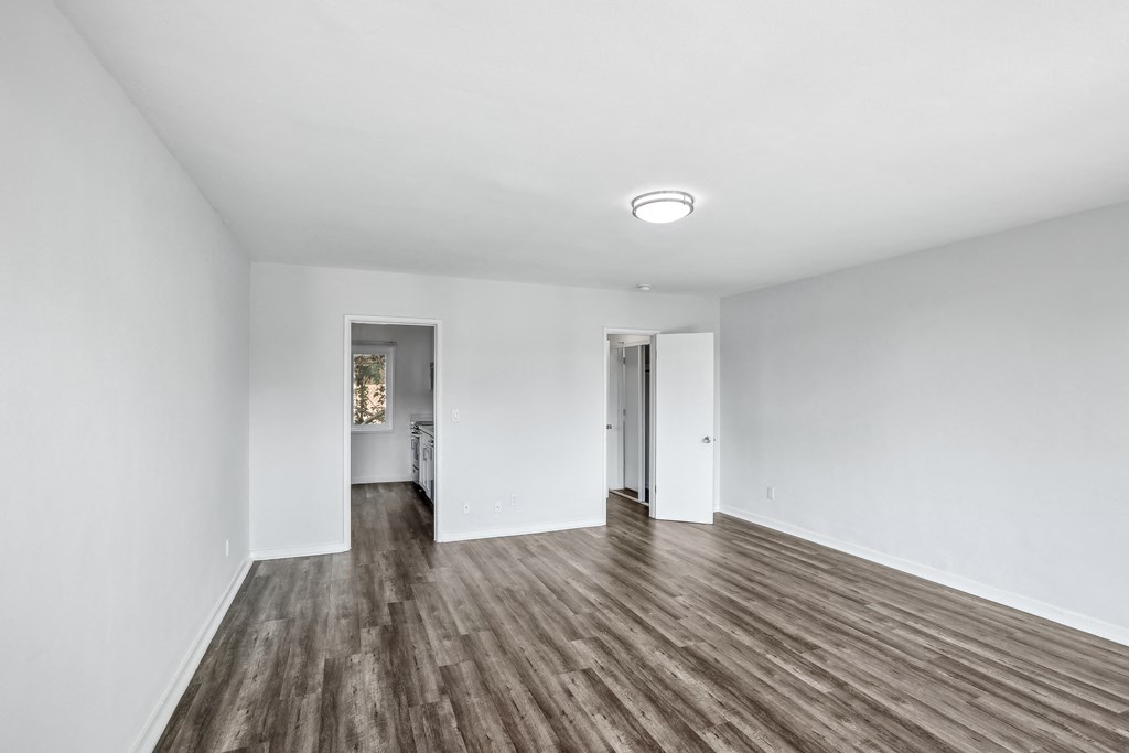 a bedroom with hardwood floors and white walls