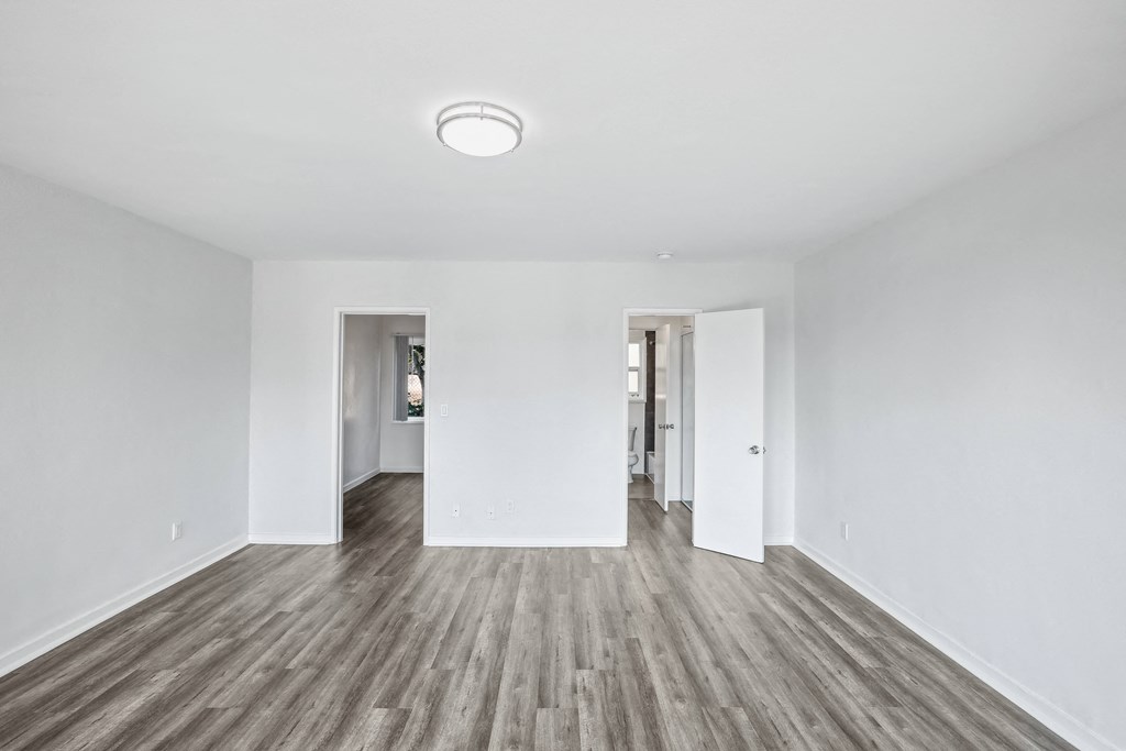 a bedroom with hardwood floors and white walls