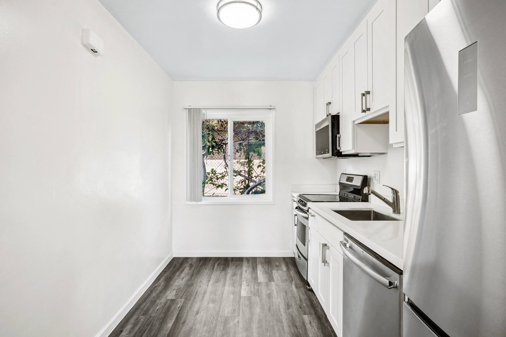 a small kitchen with white cabinets and a window