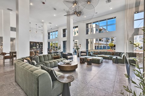 A large, modern living room with a long green couch and a circular table in the center.