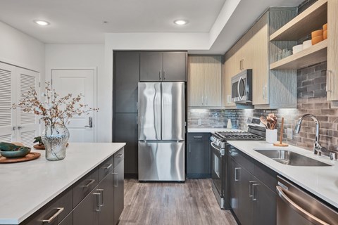 A modern kitchen with a stainless steel refrigerator and wooden cabinets.