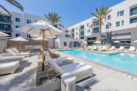 Resort style pool with lounge chairs and umbrellas at Ocean Creek Apartments, Oceanside, California