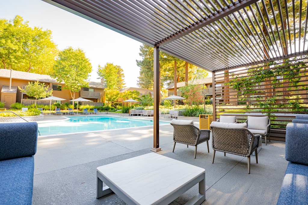 A patio with a table and chairs overlooking a pool.