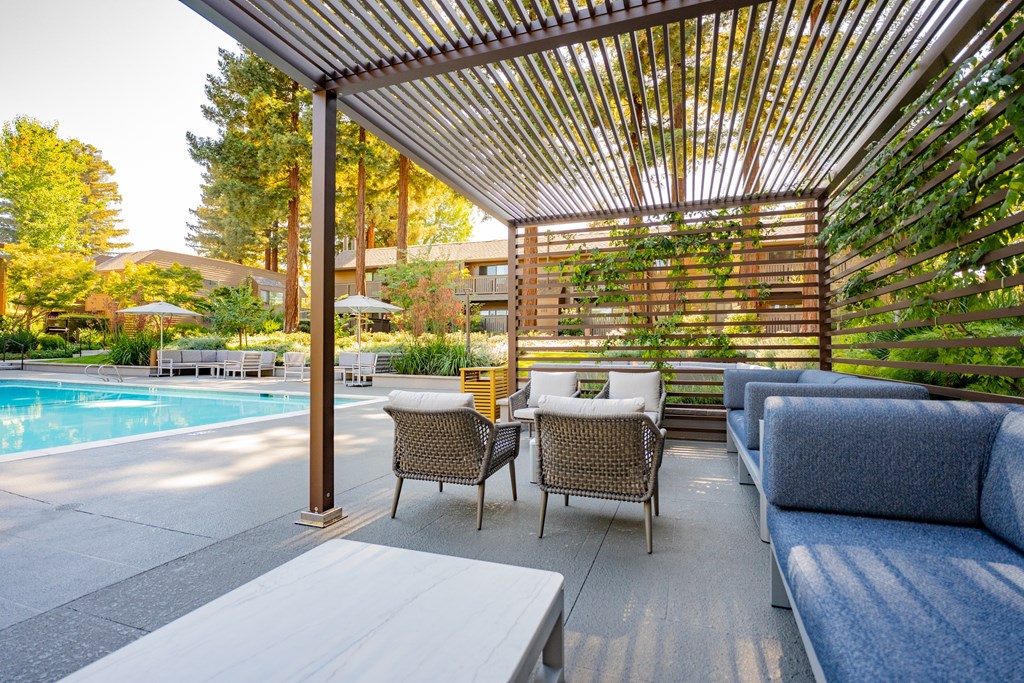 A patio with a pool and a table with chairs.