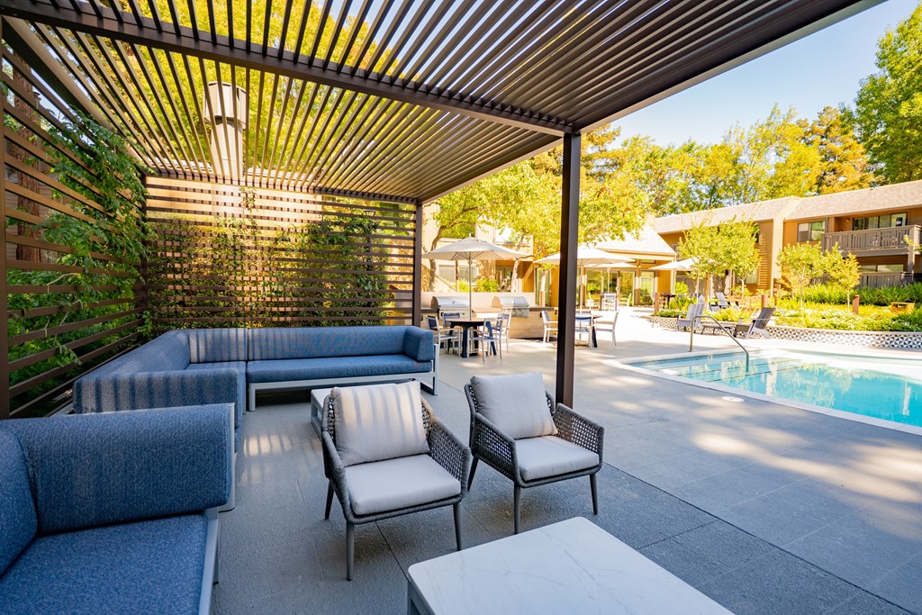 A patio with a pool and a shaded seating area.
