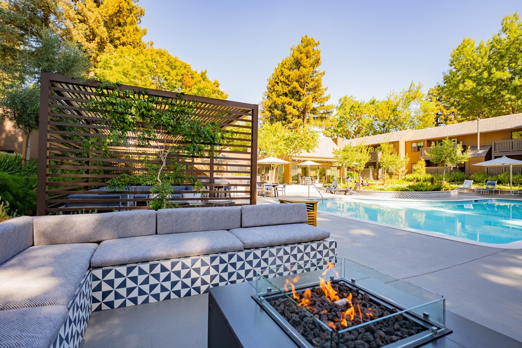 A modern outdoor patio with a fire pit and a pool.