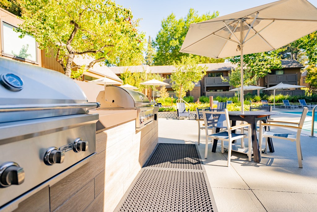 A modern outdoor kitchen with a grill and seating area.