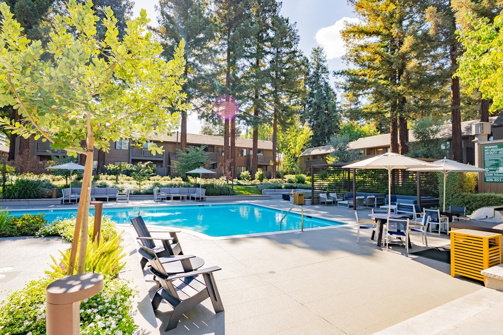 A pool surrounded by trees and chairs.