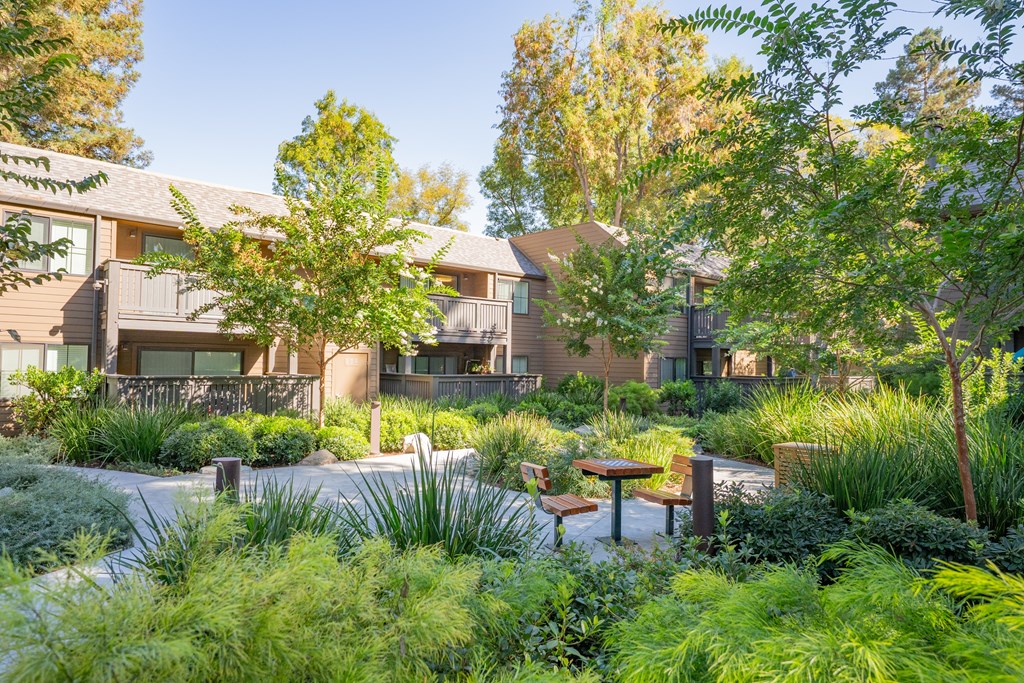 A garden with a bench and a table in front of a building.