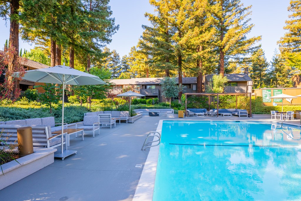 A swimming pool surrounded by trees and benches.