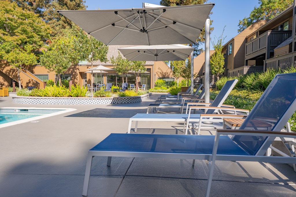 A poolside area with lounge chairs and umbrellas.