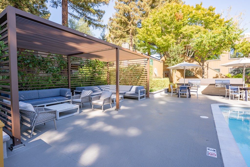 A poolside area with a shaded seating area and a pool.