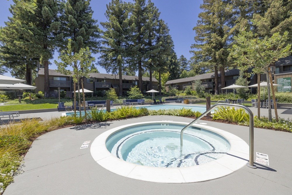 A hot tub in the middle of a grassy area with trees in the background.