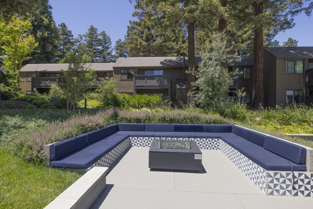 A modern house with a large backyard and a fire pit.